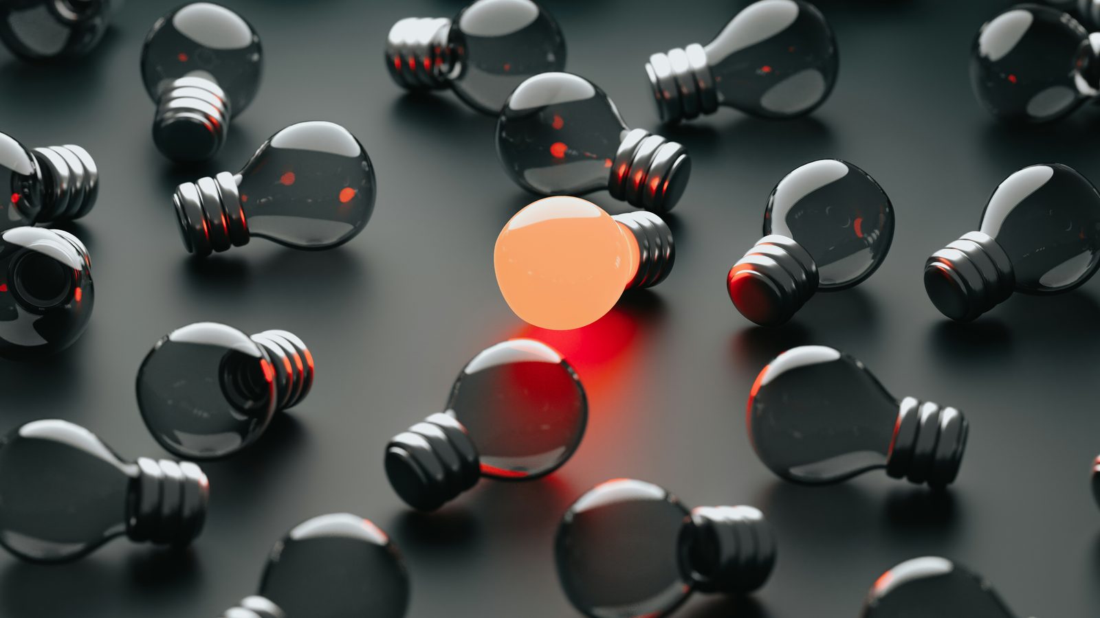 A field of dark lightbulbs with one glowing