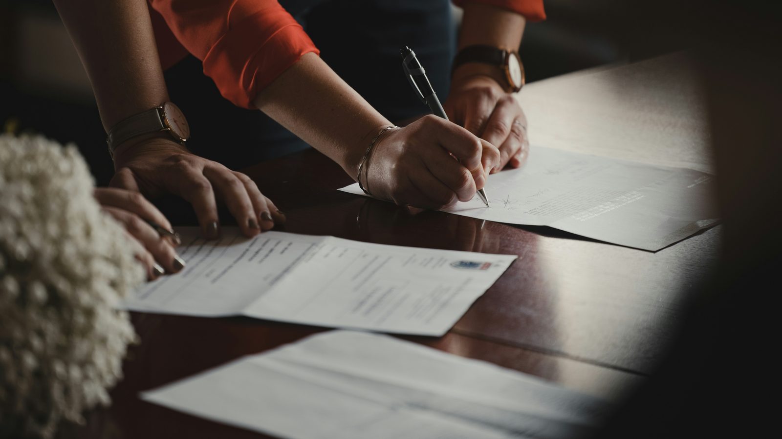 Two people signing paperwork at a desk