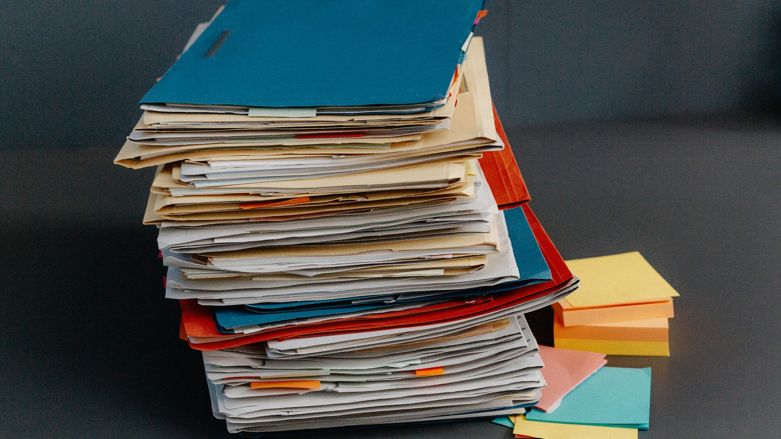 A stack of worn document folders against a dark wall